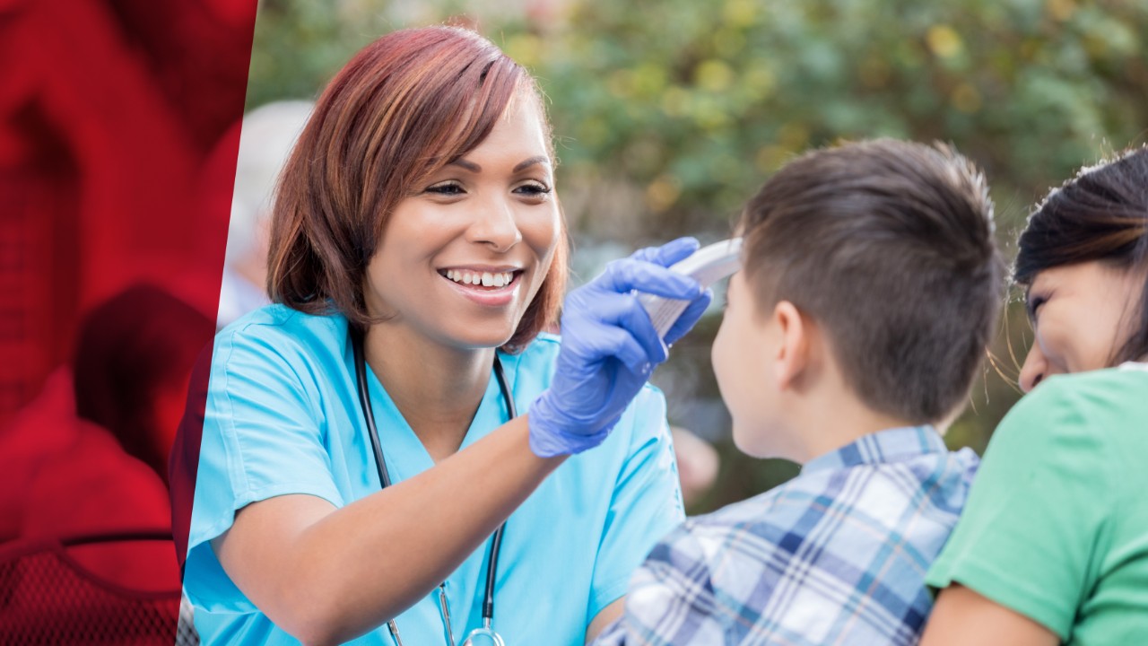 Beautiful mid adult African American nurse or doctor checks a young male patient's temperature. She is volunteering at a free outdoor clinic. She is wearing a stethoscope and scrubs.